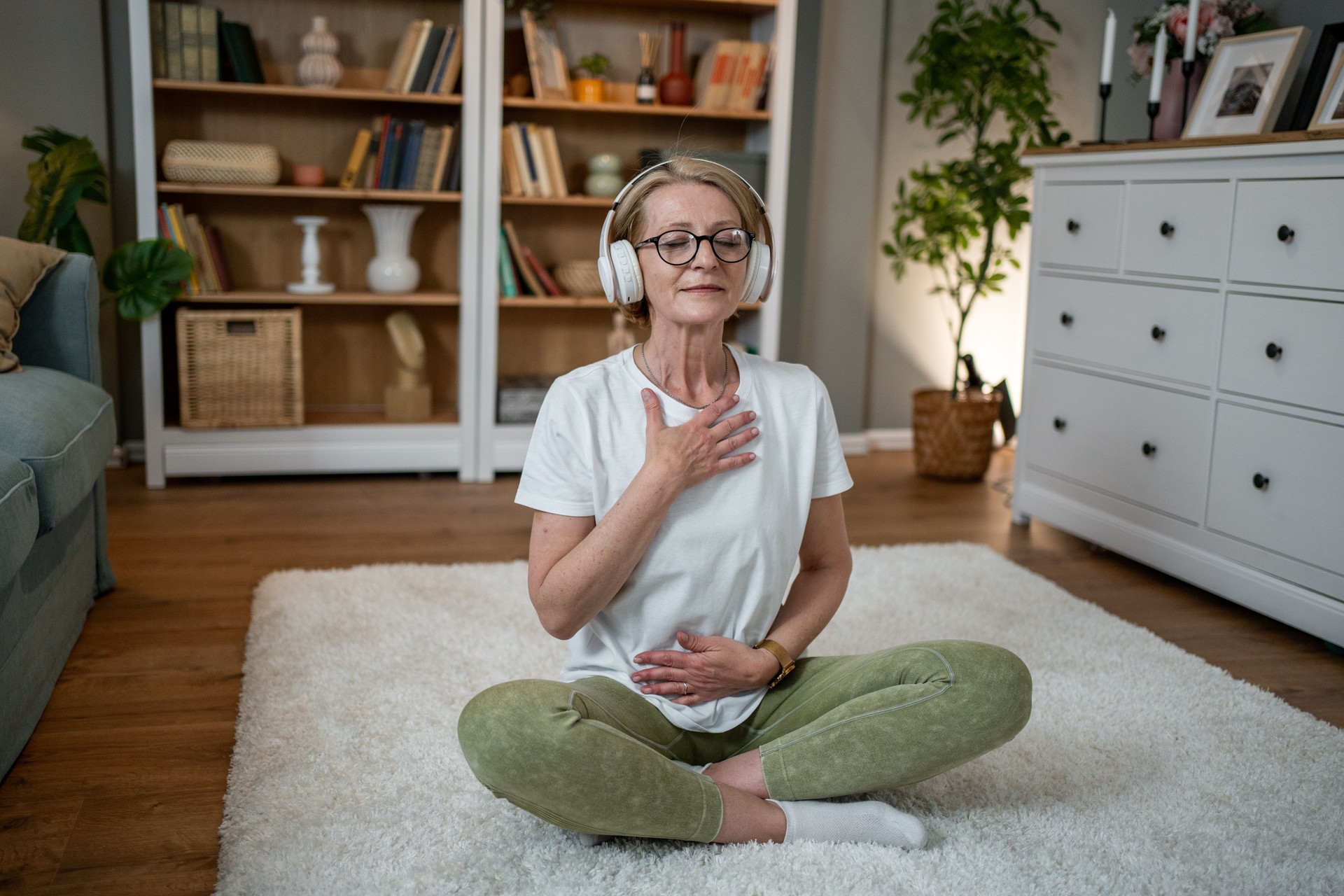 Senior woman practicing meditation with headphones at home